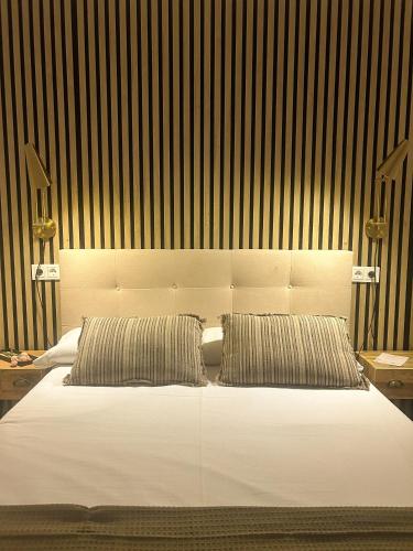 a bedroom with a white bed with two pillows at Hostal Rural Sositana in Castejón de Sos