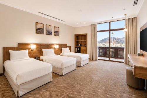 a hotel room with two beds and a desk at فندق تيلا TeeLA HoTeL in Medina