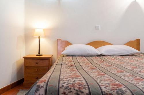 a bedroom with a bed with two pillows and a lamp at Cosy Apartment Seia 25 m² Fireplace in Seia