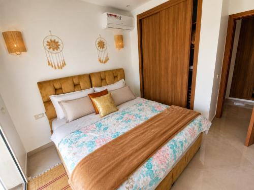 a bedroom with a large bed with a wooden headboard at Pool View Apartment Gated Residence in Sidi Rahal