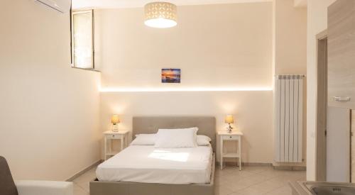 a white bedroom with a bed and two tables at Charming studio with air conditioning in Gragnano - 35 sqm in Gragnano