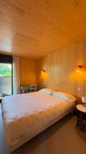 a large bed in a room with a wooden wall at Lodges Au Cœur des Puys in Nébouzat