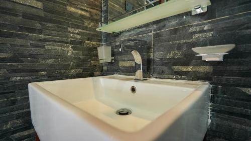 a white sink in a bathroom with a brick wall at Golden Sky Hotel & Wellness in Kandy