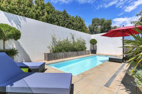 a swimming pool with a red umbrella next to a white wall at Barossa White House The West Wing in Angaston