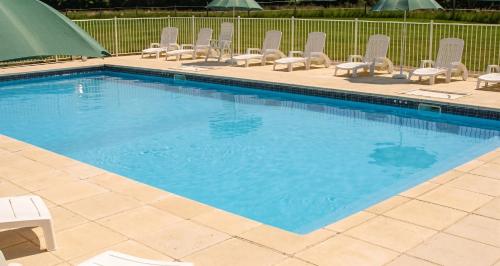 a swimming pool with chairs and a bunch of water at Maison charmante à Saint-Vincent-la-Châtre avec piscine partagée in Saint-Vincent-la-Châtre