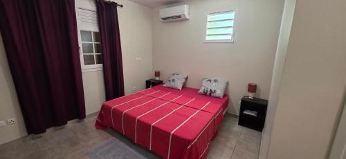 a bedroom with a red bed and a window at Villa Tidodo in Les Anses-dʼArlets