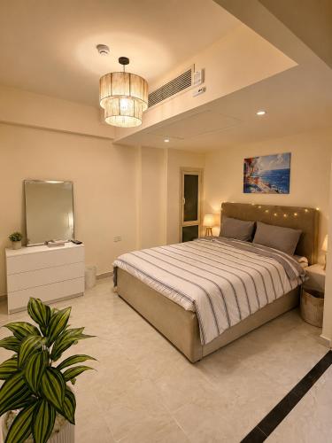 a bedroom with a large bed and a chandelier at 1 BDR Pool Front Cozy Apartment in Port Ghalib