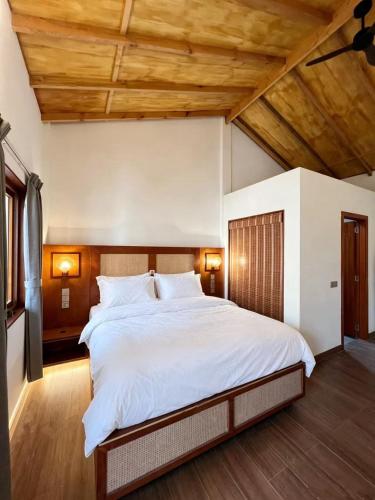 a bedroom with a large white bed with wooden ceilings at HB'S iSLAND LiFE in Mathiveri