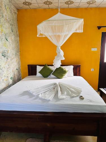 a bed with a white canopy and green pillows at Sigiriya Vee Guest in Sigiriya