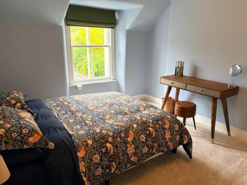 a bedroom with a bed and a desk and a window at Myrtlebank in Pitlochry