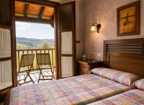 a bedroom with a bed and a balcony with a view at Hotel Rural El Verdenal in Noceda del Bierzo