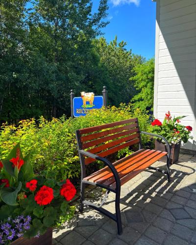 a wooden bench sitting next to a garden with flowers at Hôtel au Petit Berger in La Malbaie