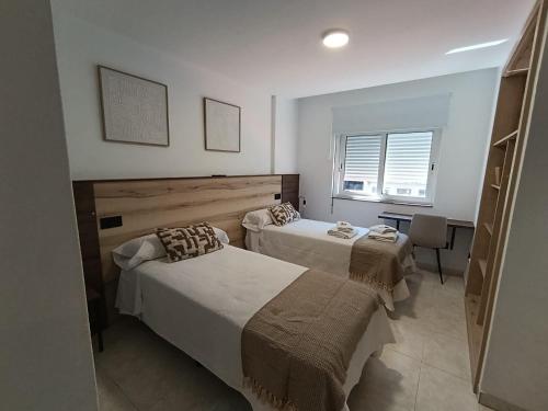 a bedroom with two beds and a table and a window at Pensión Pastoriza in Vimianzo