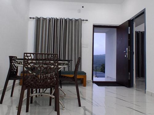 a dining room with a table and chairs and a window at Venus Valley Vagamon in Vagamon