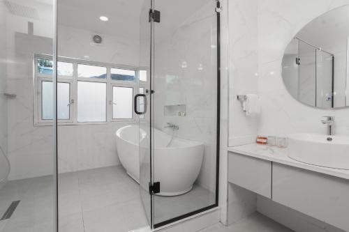 a white bathroom with a tub and a sink at Amber Residence GRA Ikeja in Ikeja