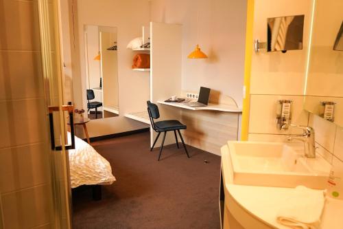 a bathroom with a sink and a desk with a laptop at Logis Hôtel Restaurant Au Lion Rouge in Bartenheim