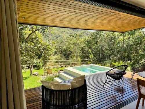 a deck with a swimming pool and two chairs at Arandu Bangalô in Cavalcante