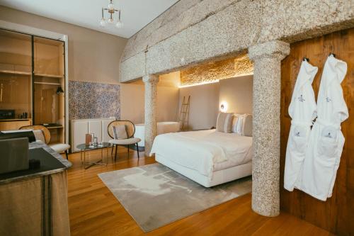 a bedroom with a large bed with a stone wall at Torel Royal Court in Guimarães