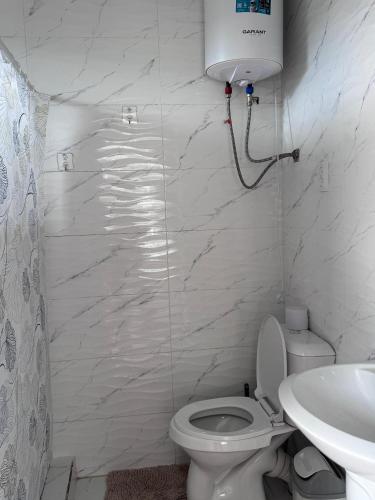 a white bathroom with a toilet and a sink at Maximus in Bokonbayevo