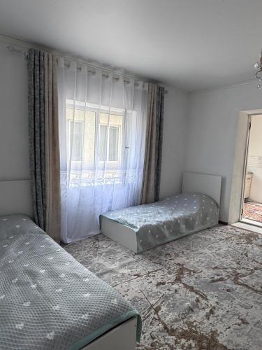 a bedroom with two beds and a window at Maximus in Bokonbayevo