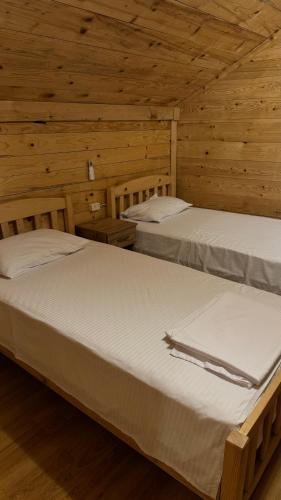 two beds in a room with wooden walls at Red Roofs in K'eda
