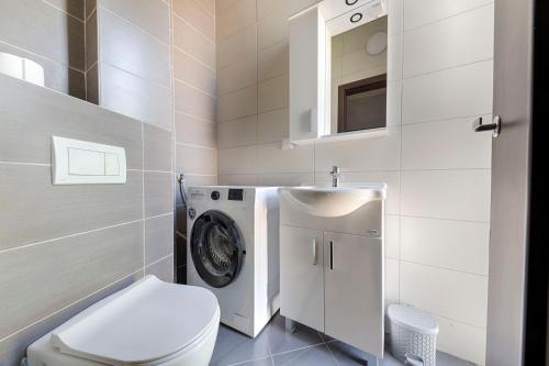a bathroom with a toilet and a washing machine at Villa & Pool in Utjeha