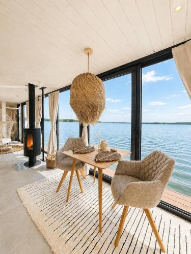 a living room with a table and chairs and a view of the water at Bohéa Spa Hausboot mit Sauna und Kamin in Schwielochsee