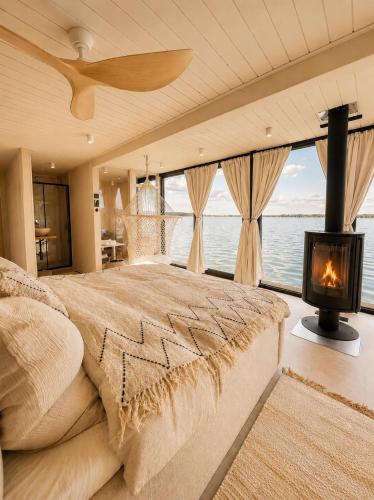 a bedroom with a large bed and a fireplace at Bohéa Spa Hausboot mit Sauna und Kamin in Schwielochsee