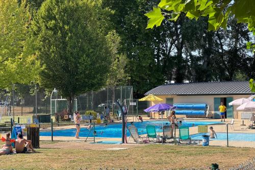 a group of people sitting around a swimming pool at Camping Onlycamp Port Sainte Marie in Malicorne-sur-Sarthe