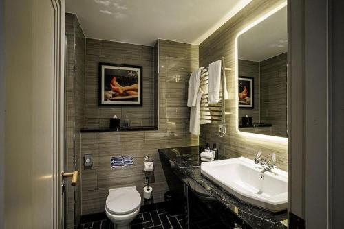 a bathroom with a sink and a toilet and a mirror at The Rex - formerly Hotel Gotham in Manchester
