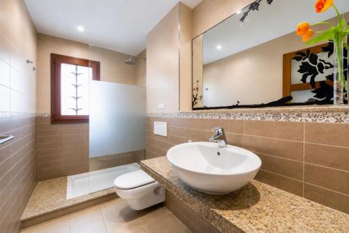 a bathroom with a sink and a toilet and a mirror at Villa Binimelis in Cacla D'or