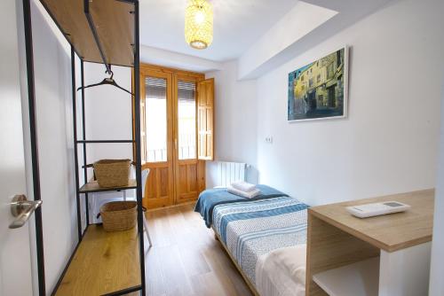a small bedroom with a bed and a desk at Balcón de los Herreros in Cuenca