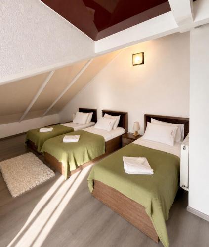 two beds in a room with green sheets at Vernisa Hotel in Tbilisi City