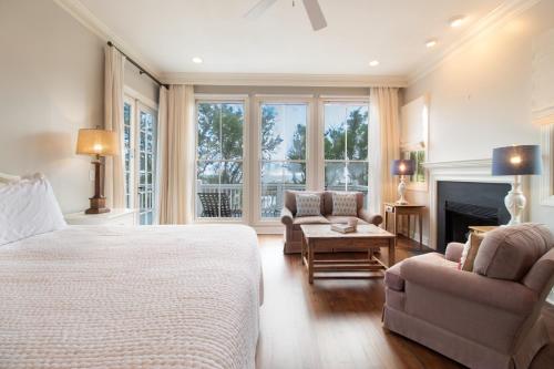 a bedroom with a bed and two chairs and a fireplace at Chiltren By The Sea in Edisto Island