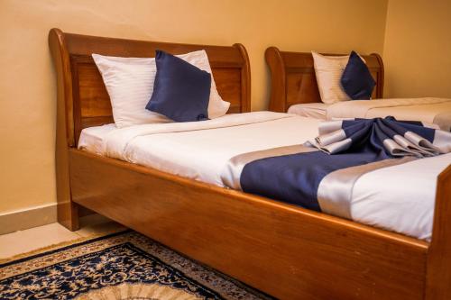 two beds with blue pillows on them in a room at Sandton hotel kasese in Nalakonge
