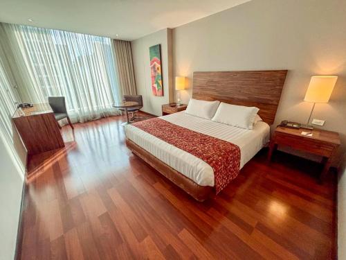 a hotel room with a large bed and wooden floors at Hotel Estelar Calle 100 in Bogotá