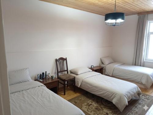 a room with two beds and a chair and a table at HUSAYN HoSTEL in Xirdalan