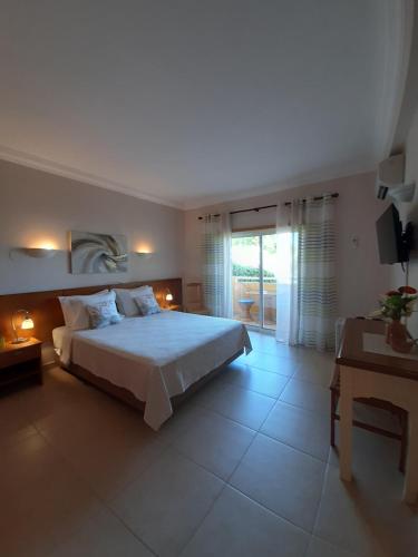 a bedroom with a bed and a desk and a television at Lucie Lime GuestHouse in Luz