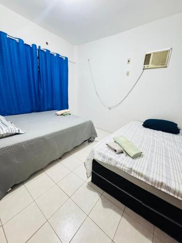 two beds in a room with blue curtains at Apartamento No Centro de Gurupi Essenza in Gurupi