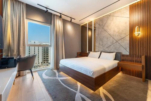 a bedroom with a bed and a desk and a window at Yas Island Luxury Apartment by City homes in Yas Island
