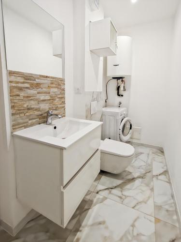 a white bathroom with a toilet and a sink at Mermaid Beach in Roquebrune-Cap-Martin