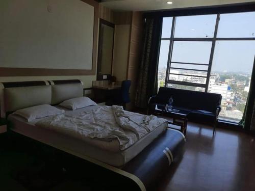 a bedroom with a bed and a large window at Hotel Haven Intercontinental in Agartala