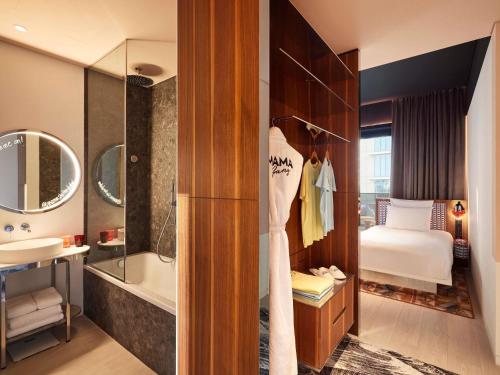 a bathroom with a bath tub and a bedroom at Mama Shelter Dubai in Dubai