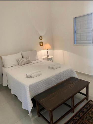 a bedroom with a large white bed with a table at Casa Charme in Brotas