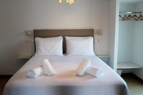 a bed with two rolls of towels on it at Lyra Apartments Tilos in Livadia