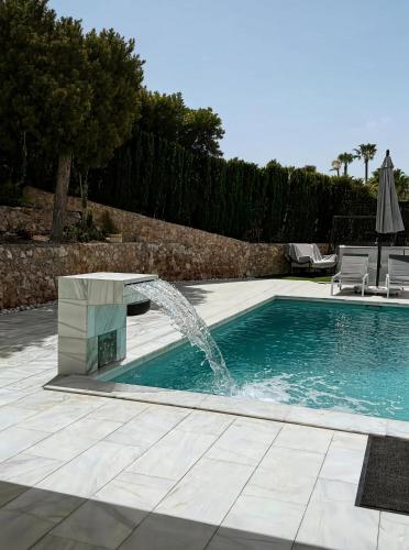 a pool with a water fountain in a yard at Villa Capitan in Orihuela Costa