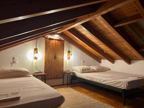 two beds in a room with wooden ceilings at La casa di Kapo in Syvota