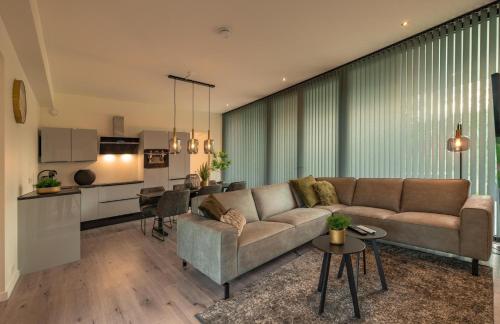 a living room with a couch and a kitchen at Forest Lodge 6 persons #624 in Maasbree
