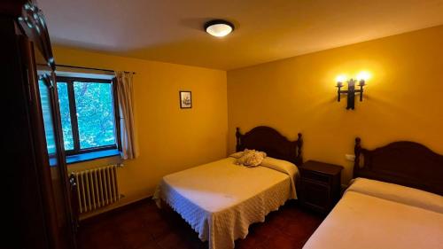 a yellow room with two beds and a window at Hotel Rural El Rincón de Trefacio in Trefacio