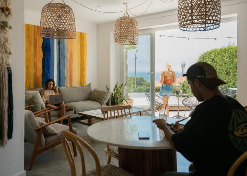two people sitting in a living room with a table at Outsite Ericeira - Boavista in Ericeira
